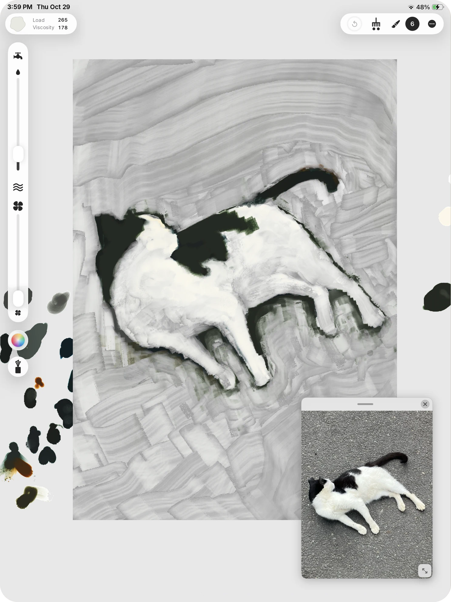 A black-and-white cat painted in grey brushwork. Dabs of mixed paint sit on the grey space beside the artboard, and a reference photo of the cat floats in a small window.